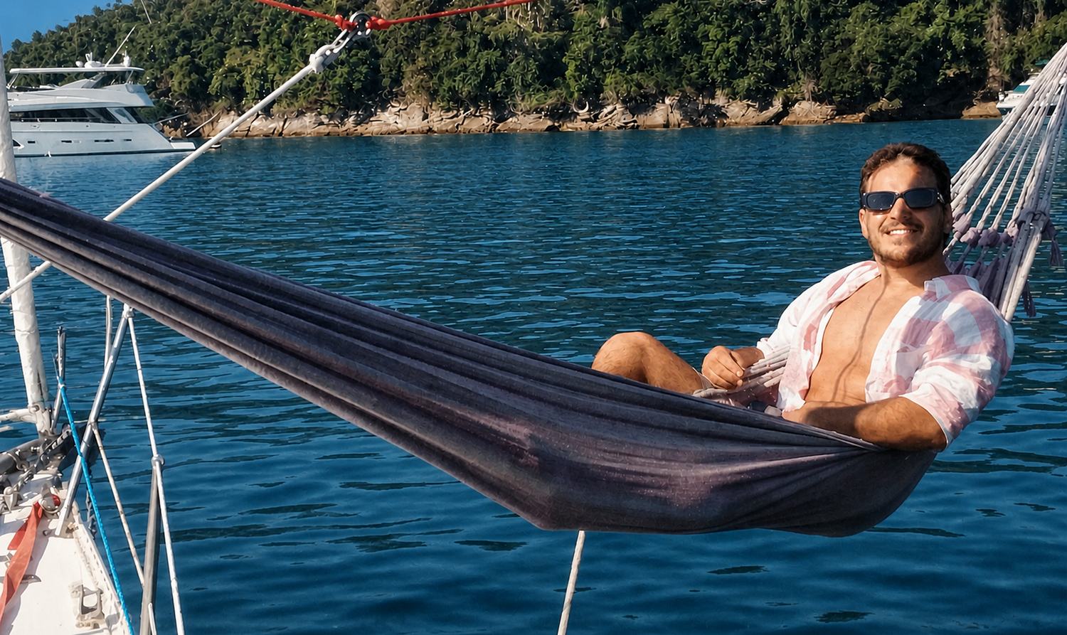 Una hamaca tendida desde el barco sobre agua turquesa, con el monte al fondo
